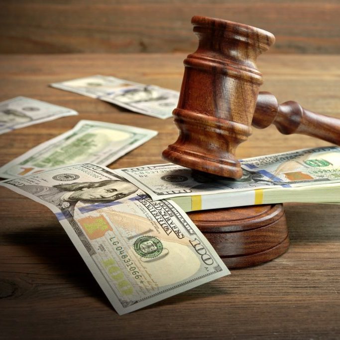 Concept For Corruption Bankruptcy Court Bail Crime Bribing Fraud Auction Bidding. Judges or Auctioneer Gavel Soundboard And Bundle Of Dollar Cash On The Rough Wooden Textured Table Background.